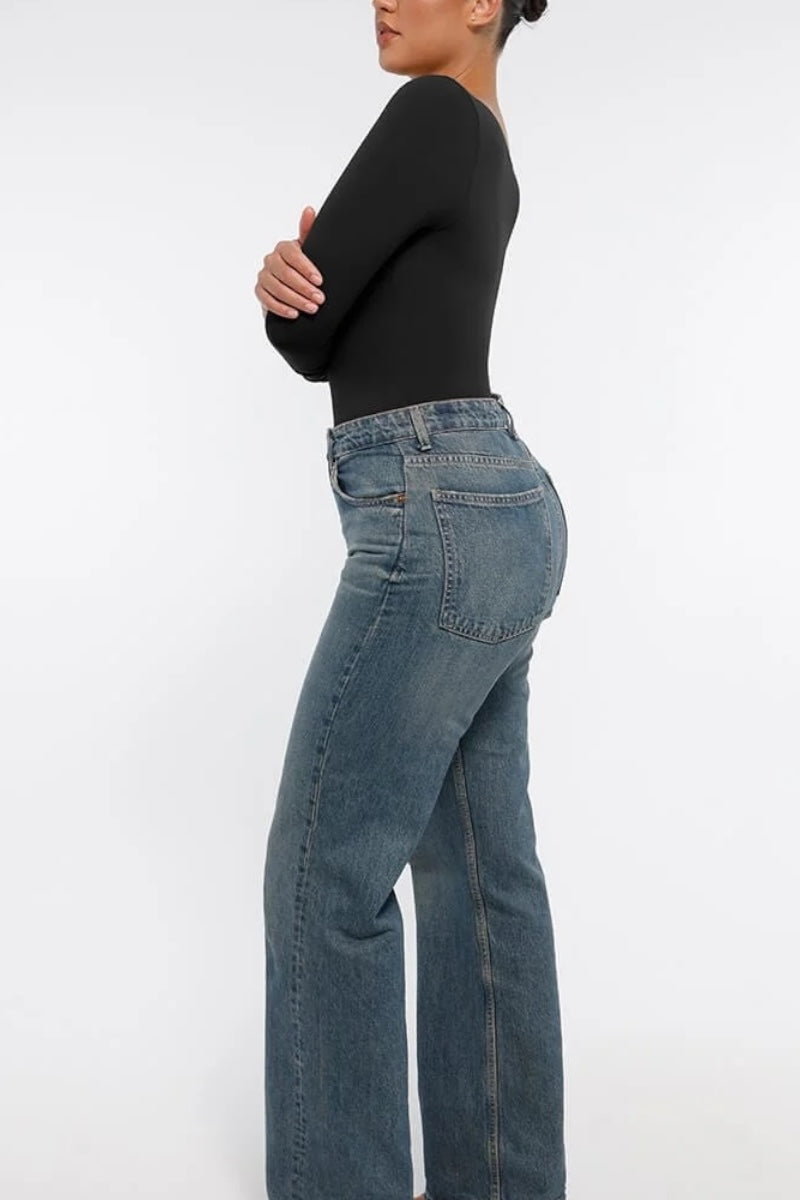 Person wearing blue jeans and a black top on a white background