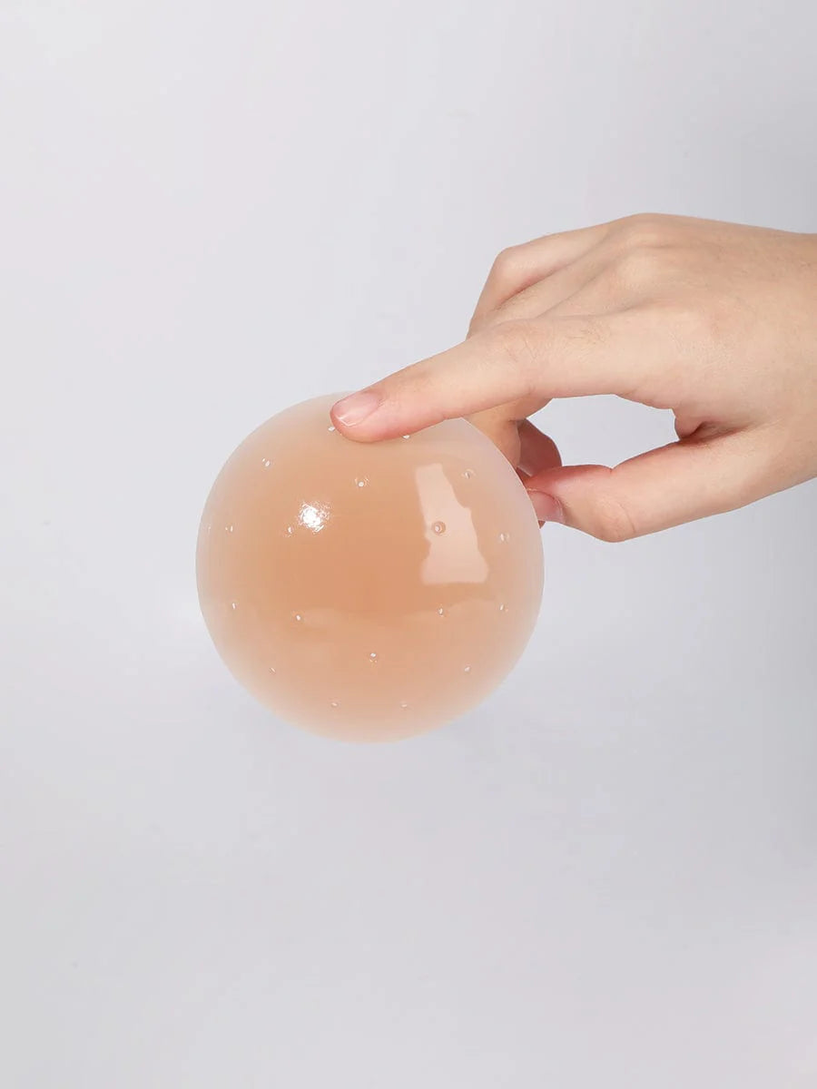 Hand holding a tan silicone pad against a light gray background