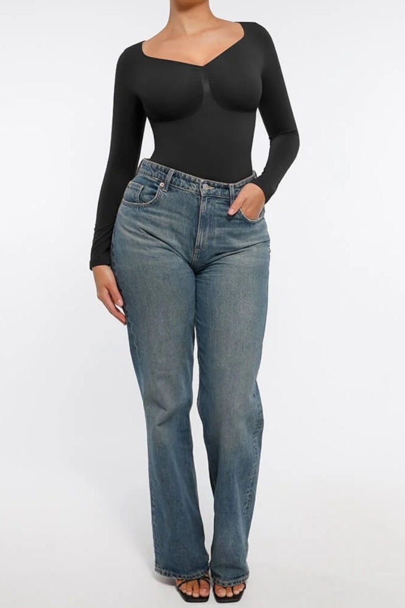Person wearing a black long-sleeve top and blue jeans on a white background