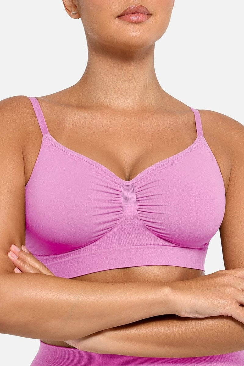 Woman wearing a pink bralette against a plain background