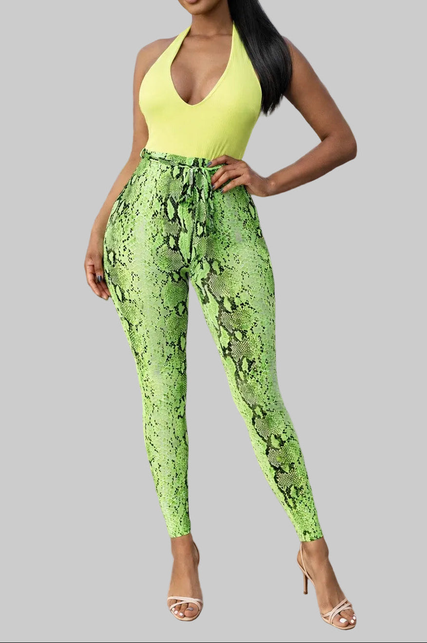 Woman wearing a bright green snake print jumpsuit on a gray background