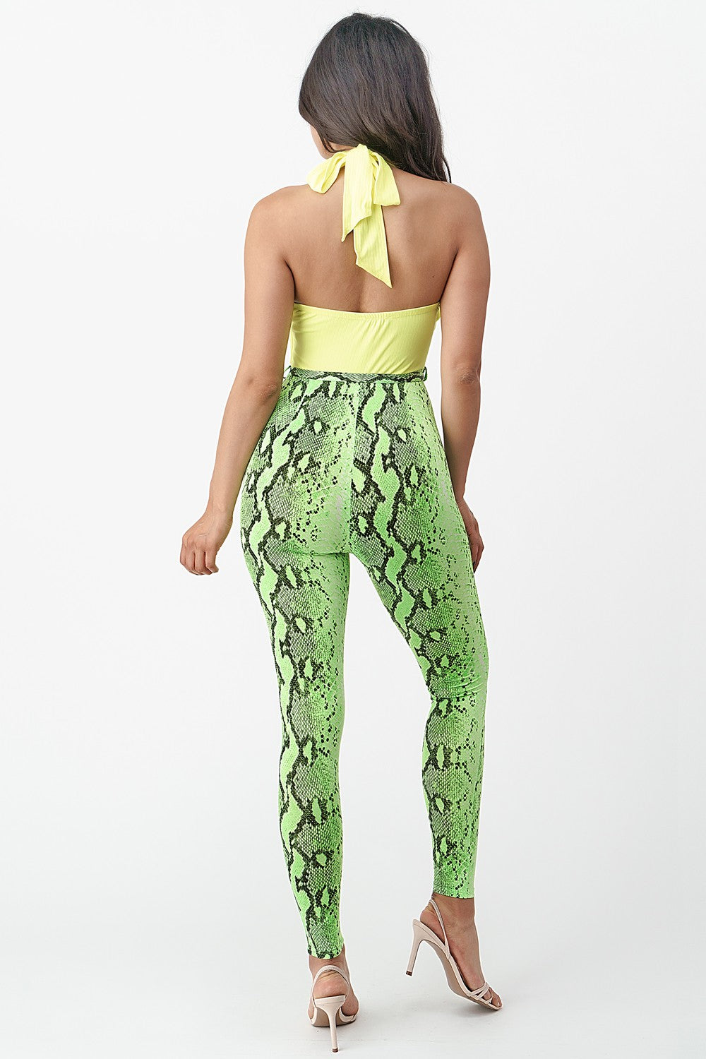 Woman wearing a green snake print jumpsuit with a yellow top on a white background