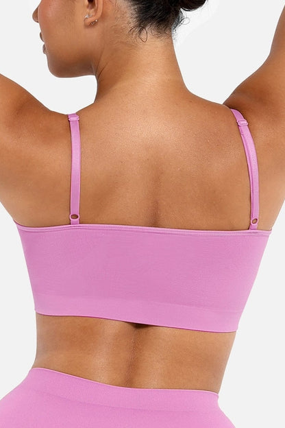 Person wearing a pink bralette and panty against a white background