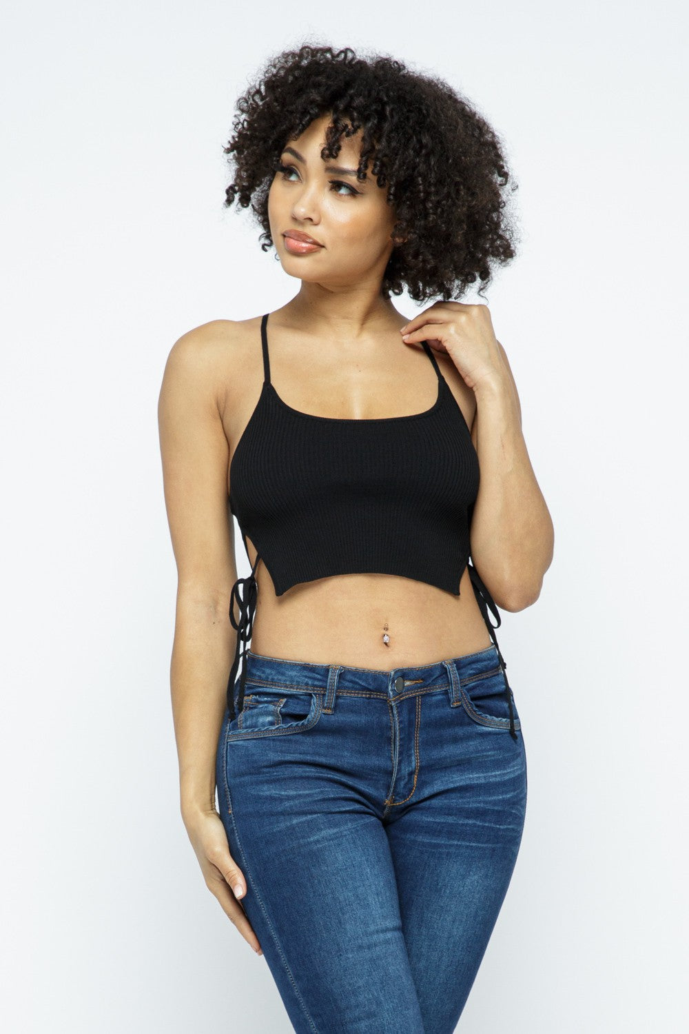 Woman wearing a black tank top and blue jeans against a white background