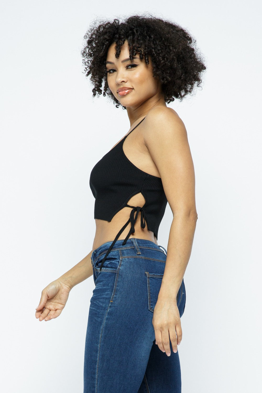 Woman wearing a black crop top and blue jeans on a white background