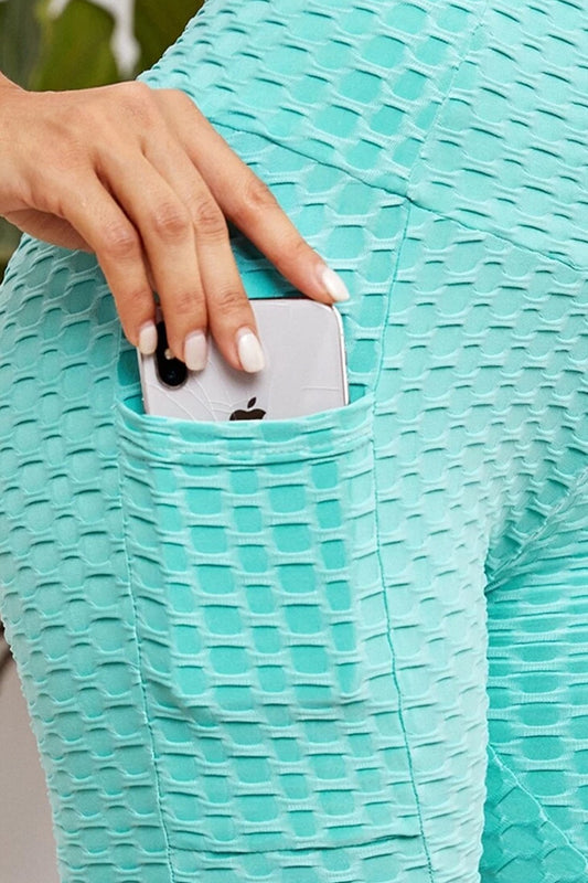Person wearing a textured teal biker shorts with a phone in a pocket.