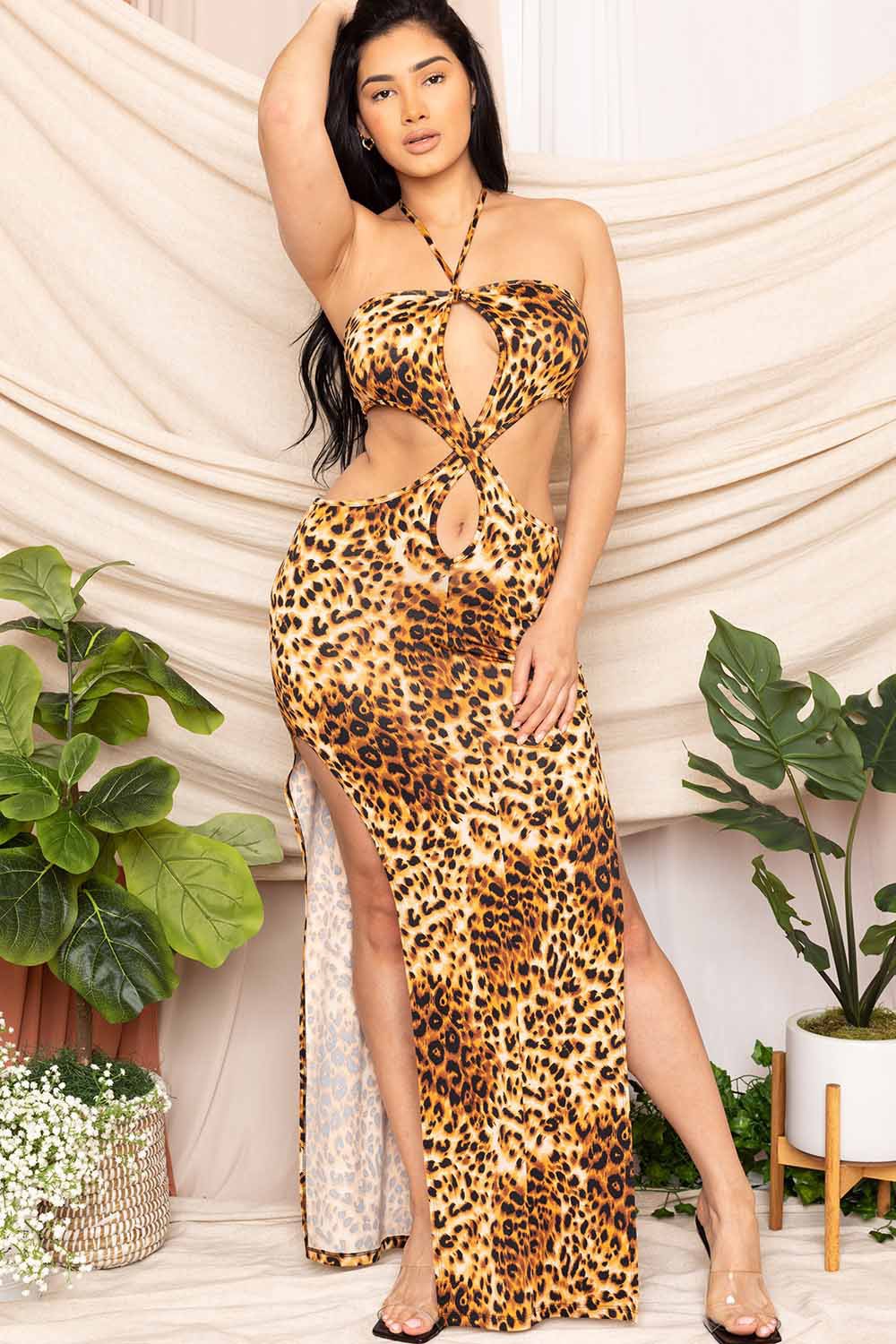 Woman wearing a leopard print dress with plants and a white curtain in the background
