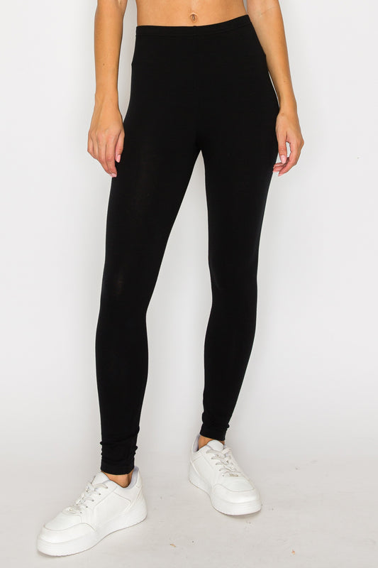 Person wearing black leggings and white sneakers on a plain background