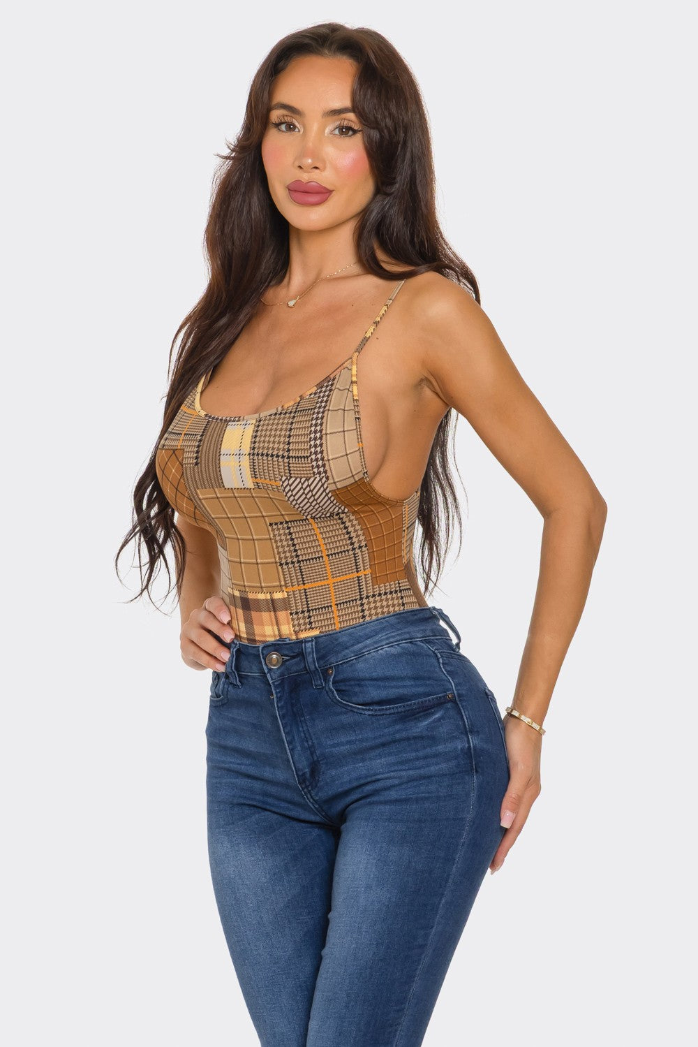 Woman wearing a plaid bodysuit and blue jeans on a white background