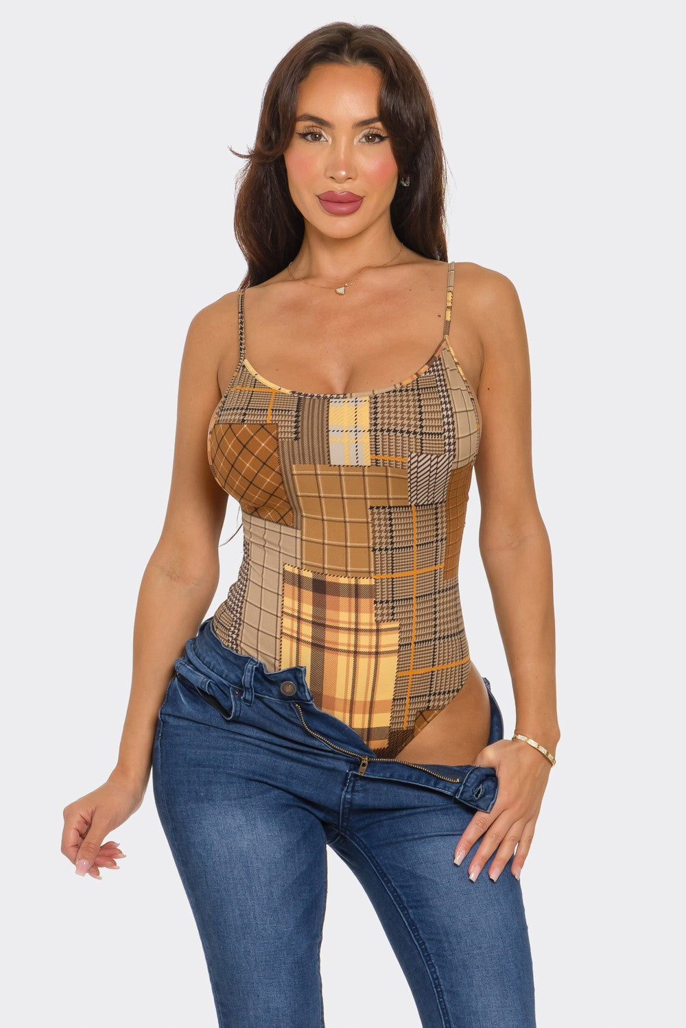 Woman wearing a plaid bodysuit and blue jeans on a white background