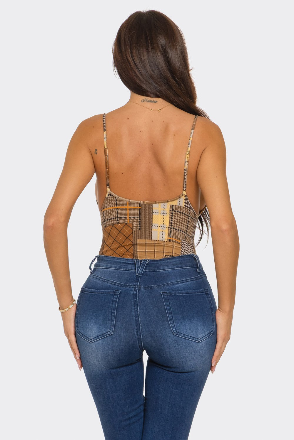 Woman wearing a plaid top and blue jeans on a white background
