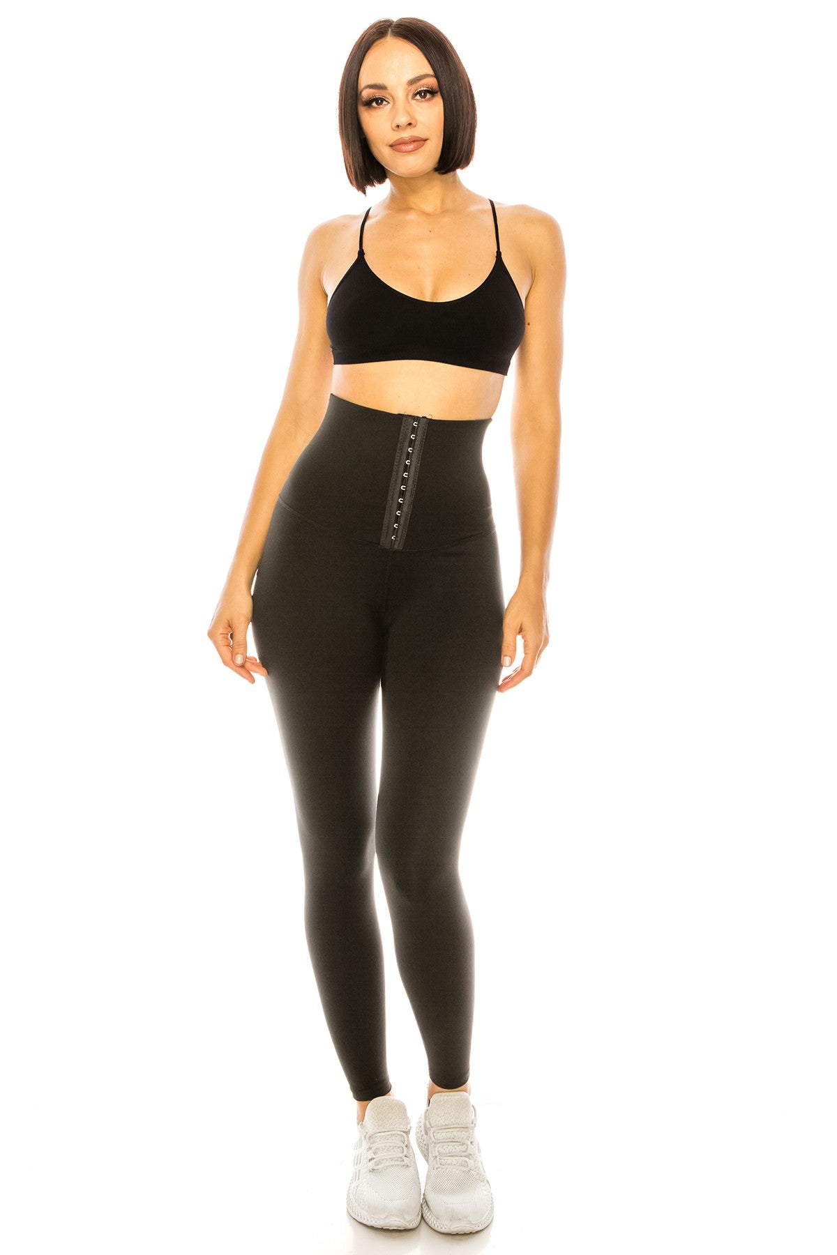 Woman wearing black sports bra and leggings on a white background