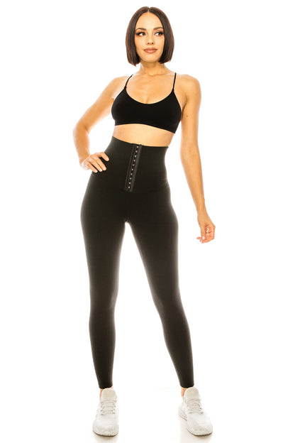 Woman wearing black sports bra and leggings on a white background