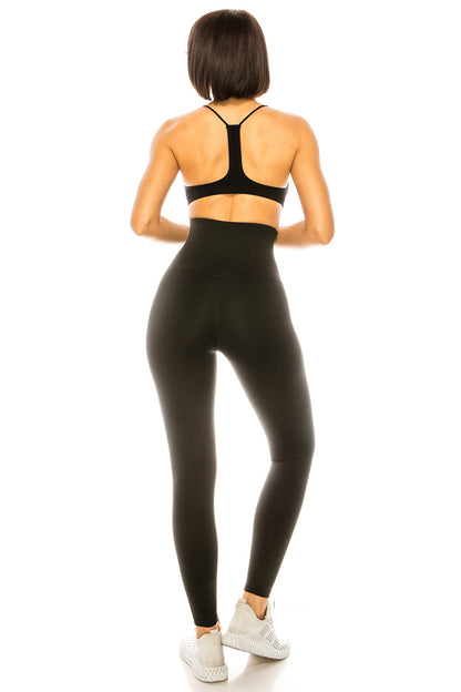Person wearing black athletic leggings and sports bra on a white background