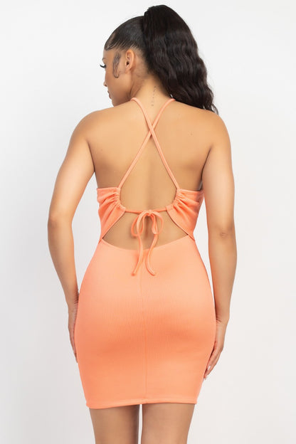 Woman wearing a peach orange dress with open back on a white background