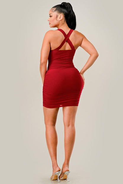 Woman wearing a red dress with crossed straps on a plain background