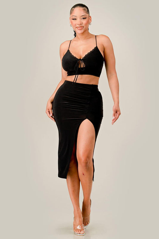 Woman wearing a black strappy top and high-waisted skirt on a plain background