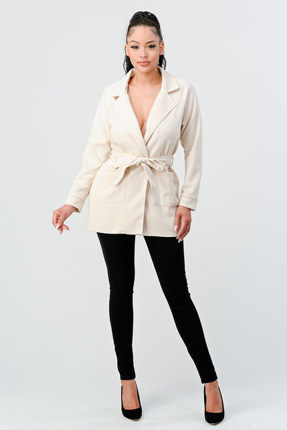 Woman wearing a cream blazer over a black top on a white background