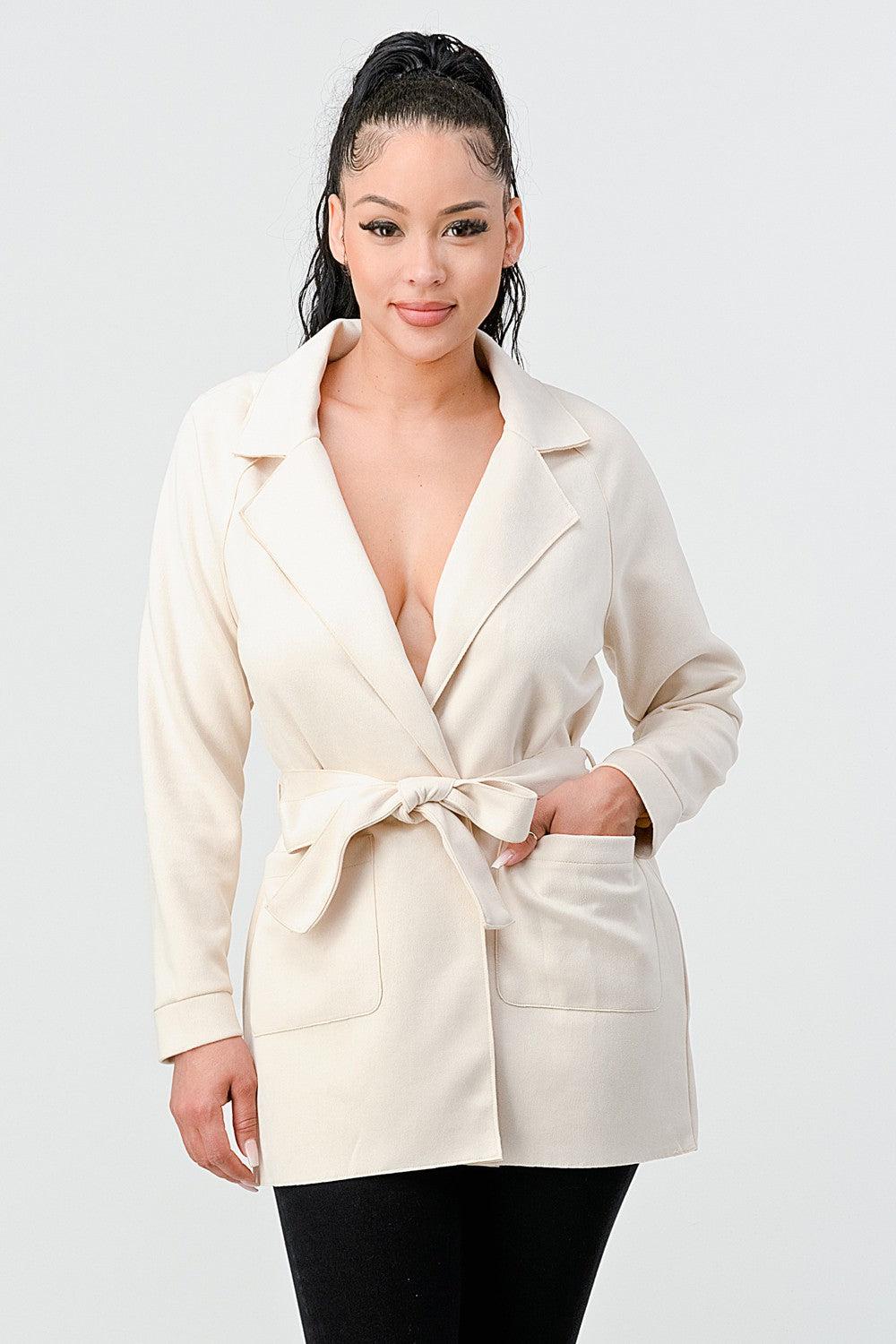 Woman wearing a cream-colored blazer with a belt on a white background