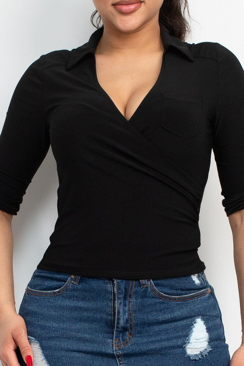 Person wearing a black top with a V-neck and three-quarter sleeves, paired with blue jeans.