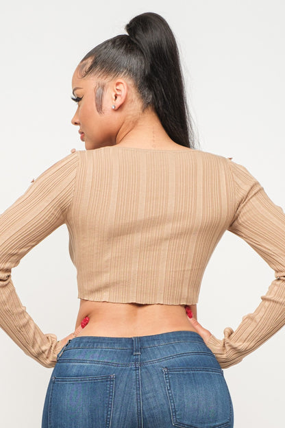 Woman wearing a long sleeve milk coffee color crop top and blue jeans on a white background