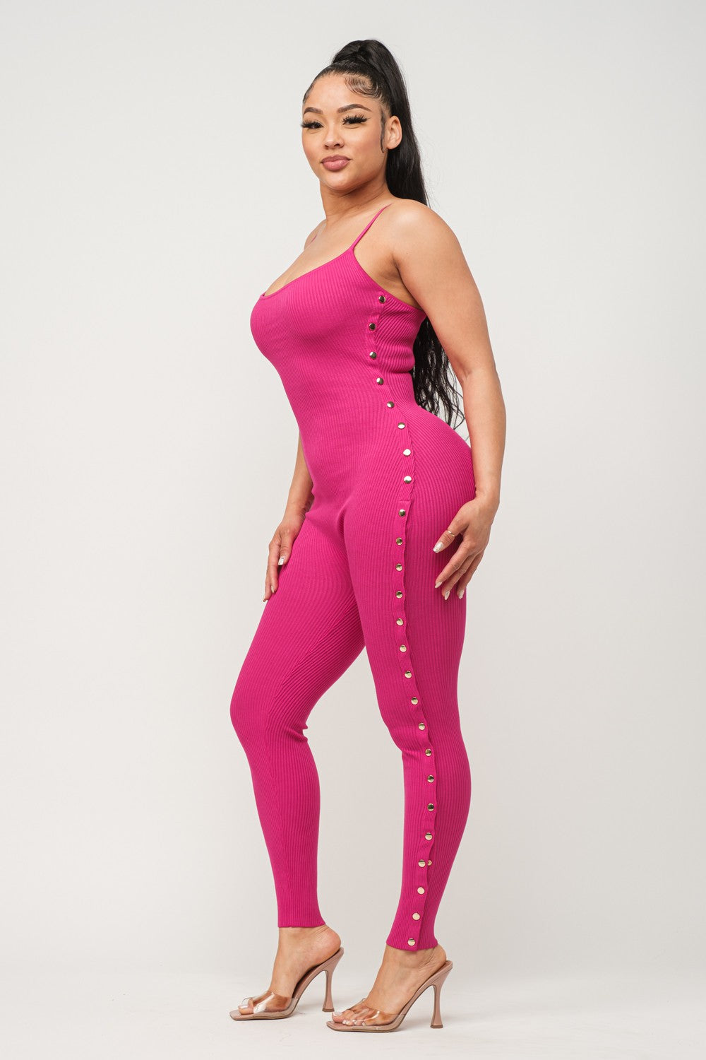 Woman wearing a fuchsia pink jumpsuit with button details on a white background