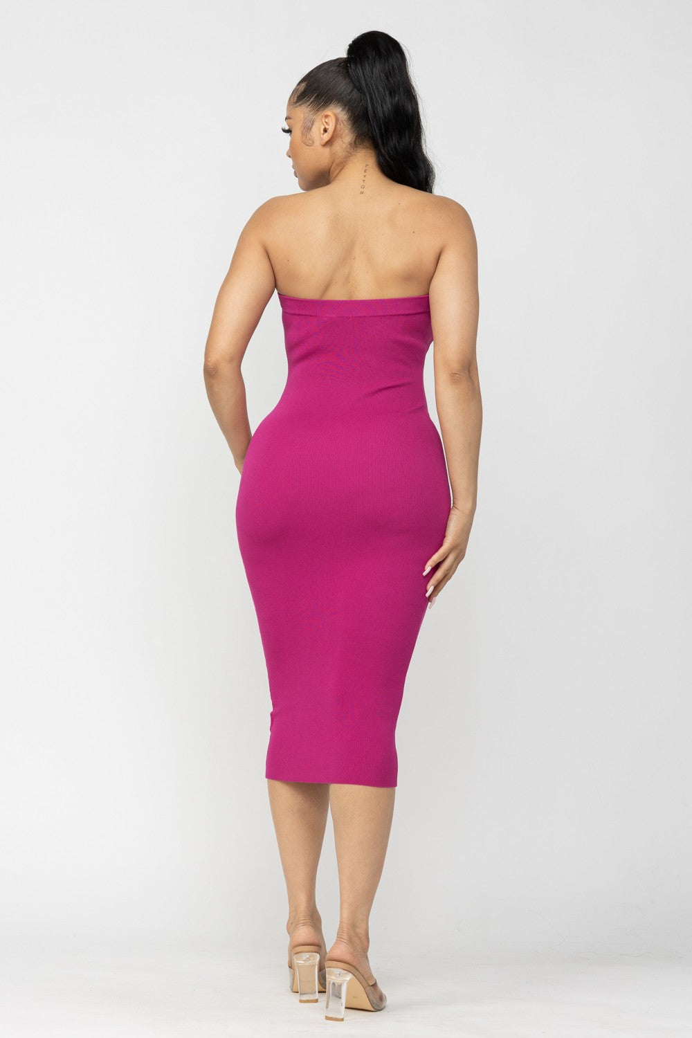 Woman wearing a strapless magenta pink dress on a white background