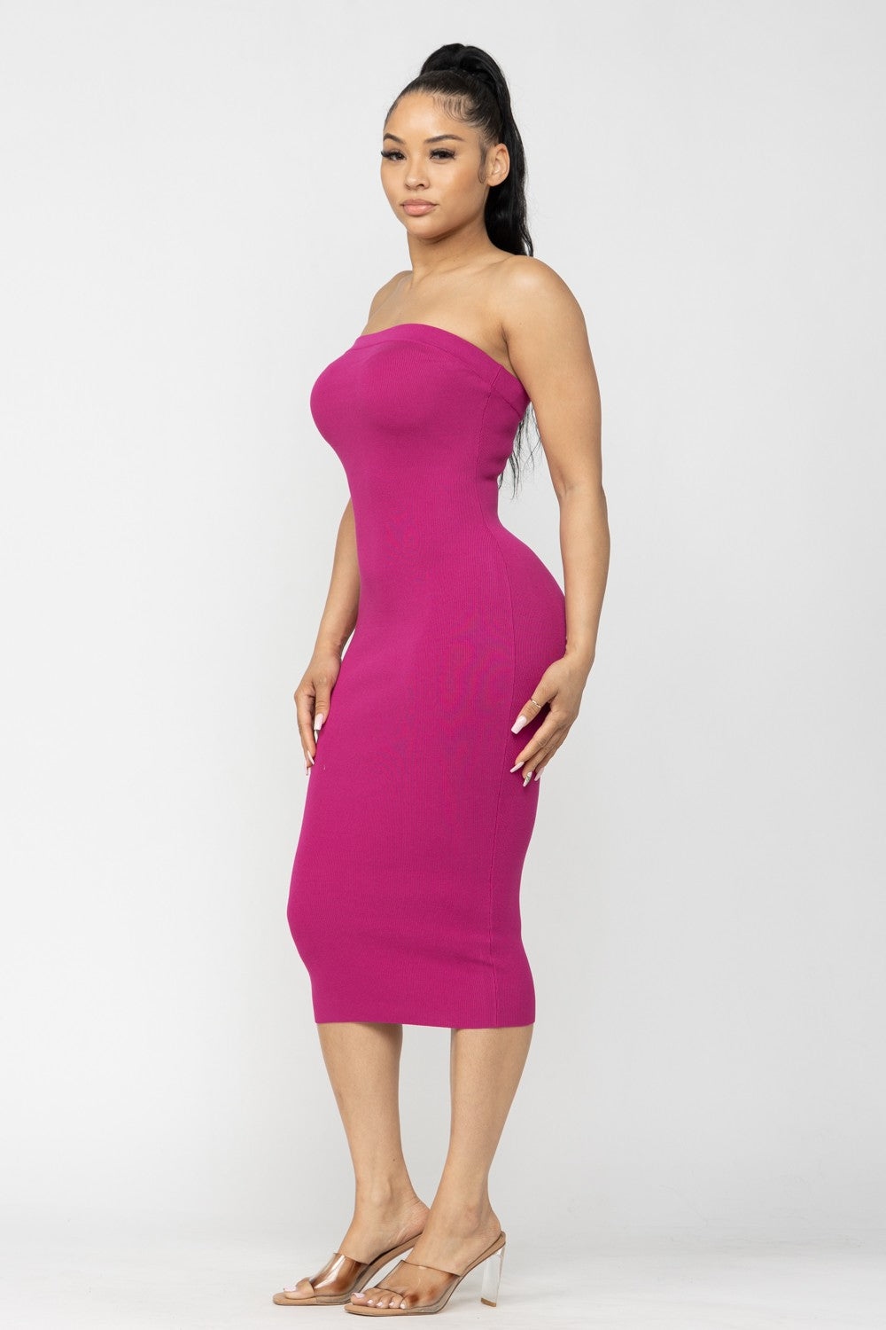 Woman wearing a strapless magenta pink dress on a white background