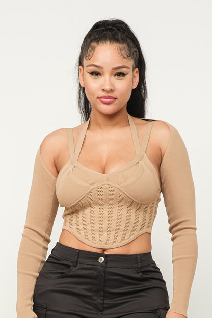 Woman wearing a long sleeve milk coffee color crop top with cut-out design and black pants on a white background