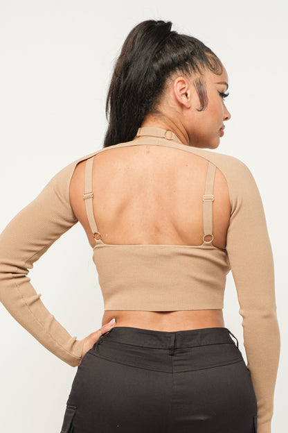 Woman wearing a long sleeve milk coffee color crop top with cut-out design and black pants on a white background