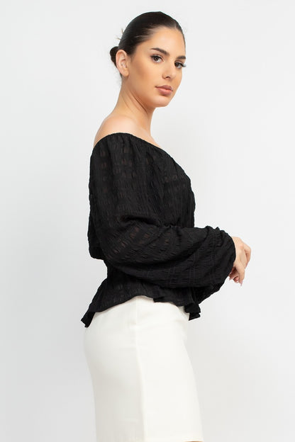 Woman wearing a black off-shoulder top and white pants on a white background