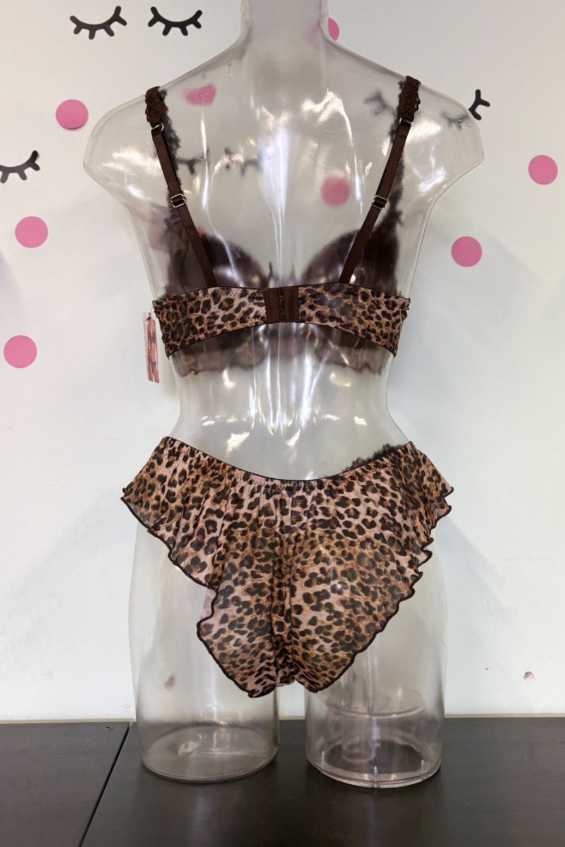 A two-piece lingerie set with a brown and beige leopard print pattern, displayed on a clear plastic mannequin torso. The set includes a ruffled bandeau top and matching ruffled high-waisted briefs.
