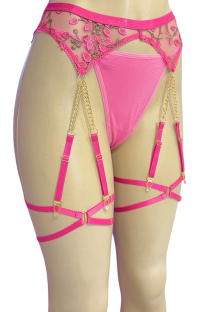 Bright pink lace and mesh garter belt with gold-tone chain and strap hardware, displayed on a beige mannequin torso against a white background.
