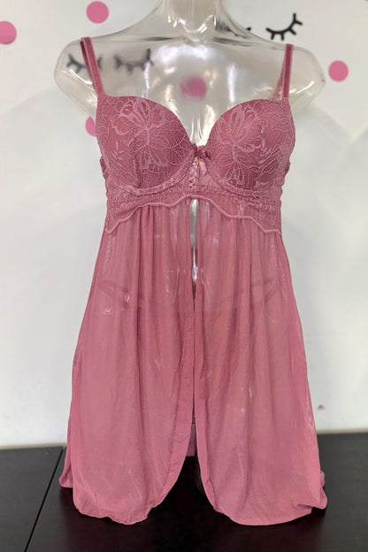 A pink sheer lingerie chemise with embroidered lace cups and thin shoulder straps, displayed on a clear mannequin torso against a white wall with pink polka dots.