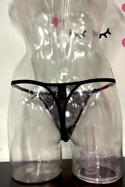 Black lace thong underwear displayed on a clear plastic female mannequin torso, with a small clear plastic cup or stand at the base.