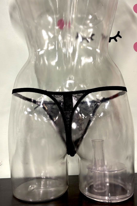 Black lace thong underwear displayed on a clear plastic female mannequin torso, with a small clear plastic cup or stand at the base.