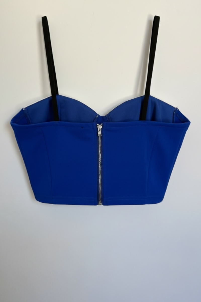 Blue crop top with black straps on a light gray background