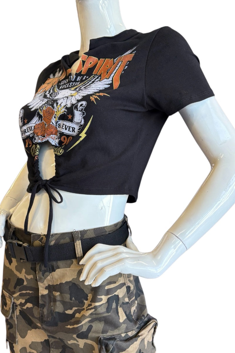A black short-sleeve crop top with a large front graphic print and side tie details, displayed on a white mannequin torso paired with a camouflage cargo skirt against a white background.