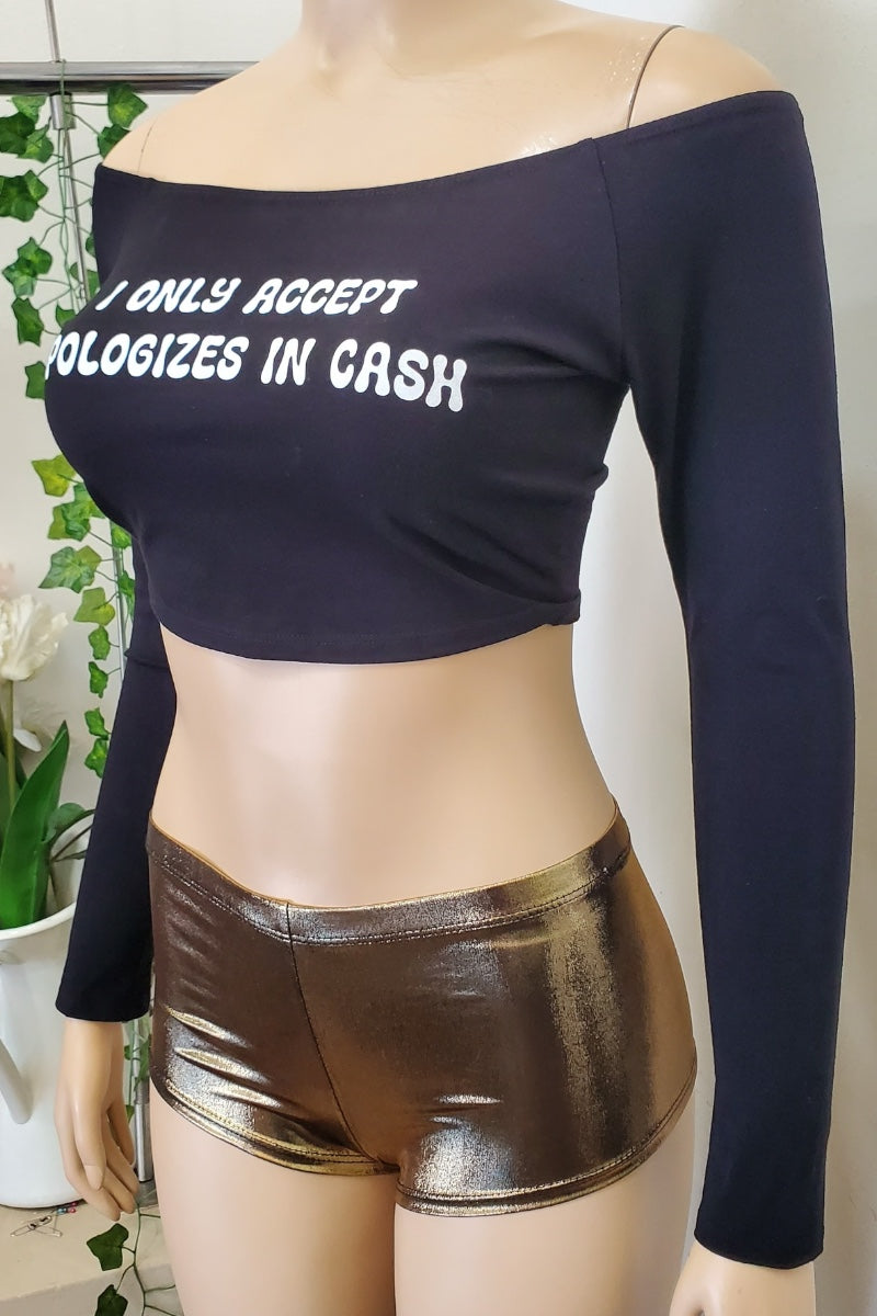 Mannequin wearing a black long-sleeve top with text and gold shorts indoors.