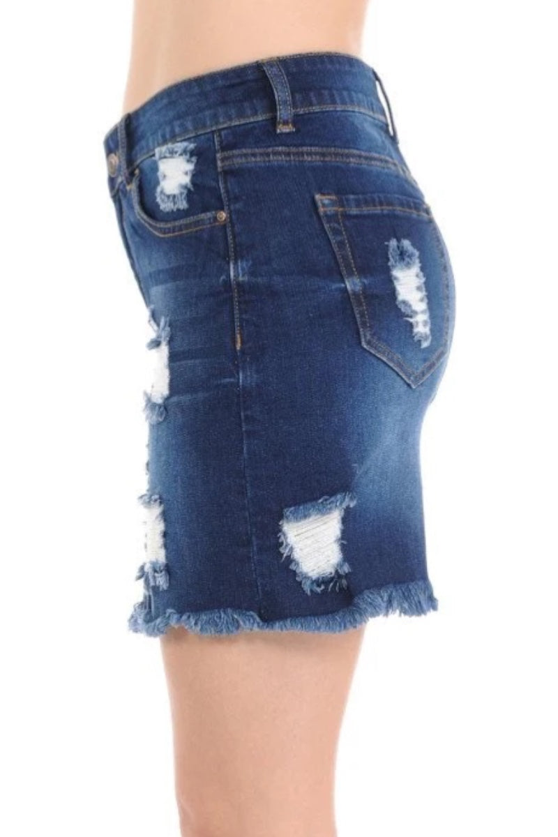 A close-up side view of a person wearing a dark blue distressed denim mini skirt with frayed hems and ripped details on the back and sides, shown against a plain white background.