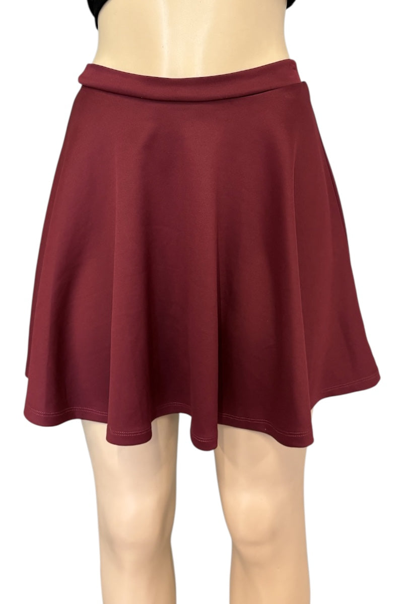 A dark burgundy flared mini skirt displayed on a beige mannequin torso and legs against a plain white background.