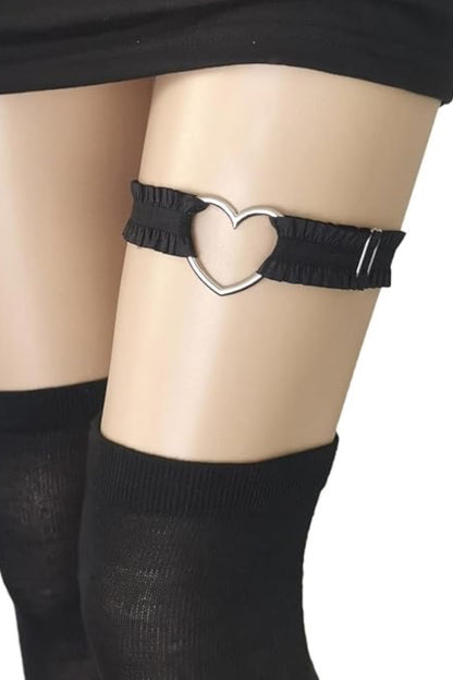 A black fabric garter belt with a silver metal heart-shaped ring, shown on a mannequin leg wearing black thigh-high socks against a white background.