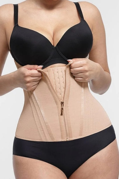 Person wearing a black bra and beige waist trainer on a white background