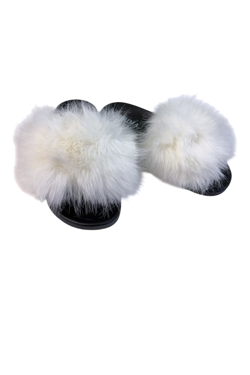 A pair of black slide sandals with oversized fluffy white fur trim, photographed on a plain white background.