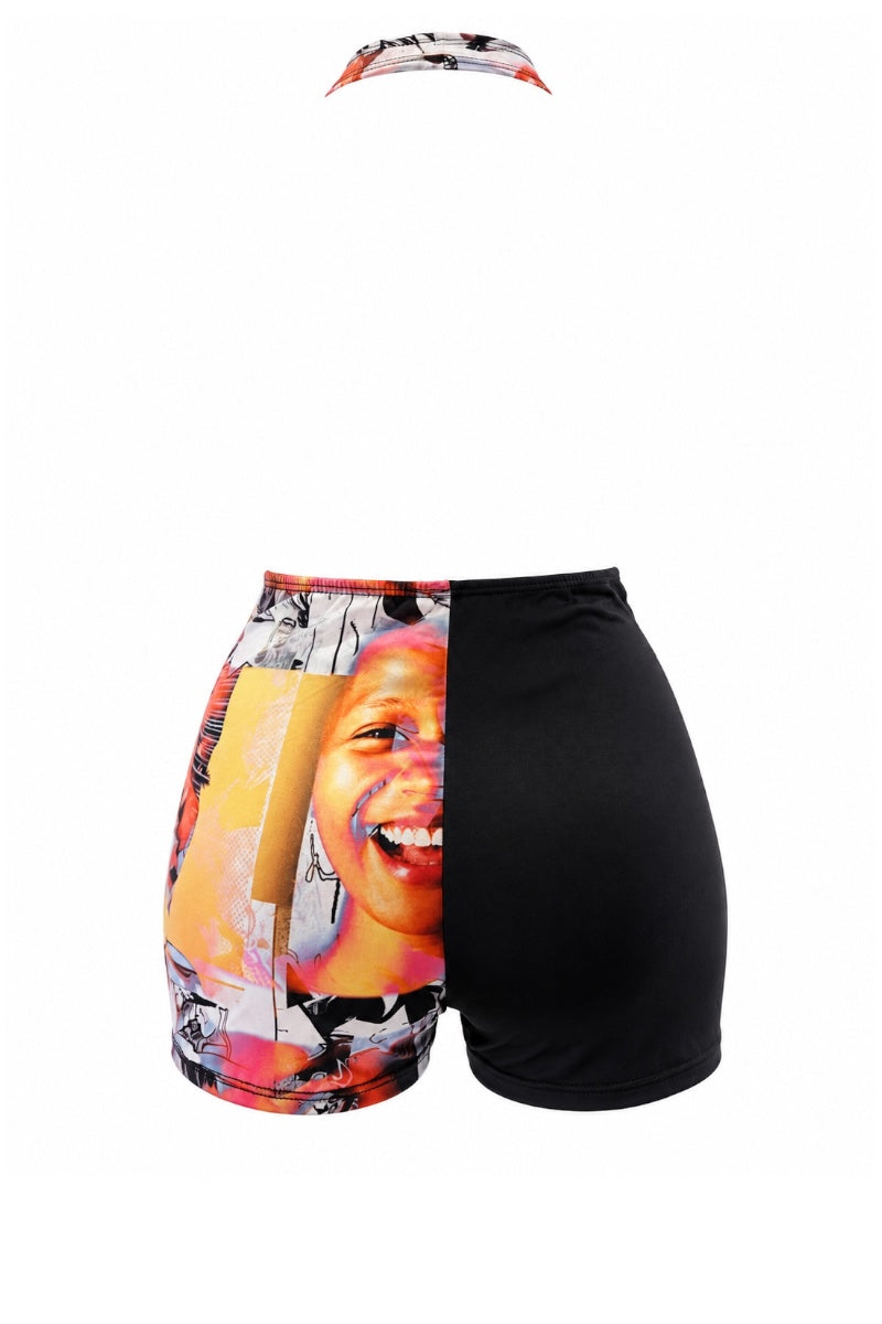 A romper featuring black shorts with a vibrant, multicolor photographic print on the left leg, paired with a matching halter neckband with the same colorful print.