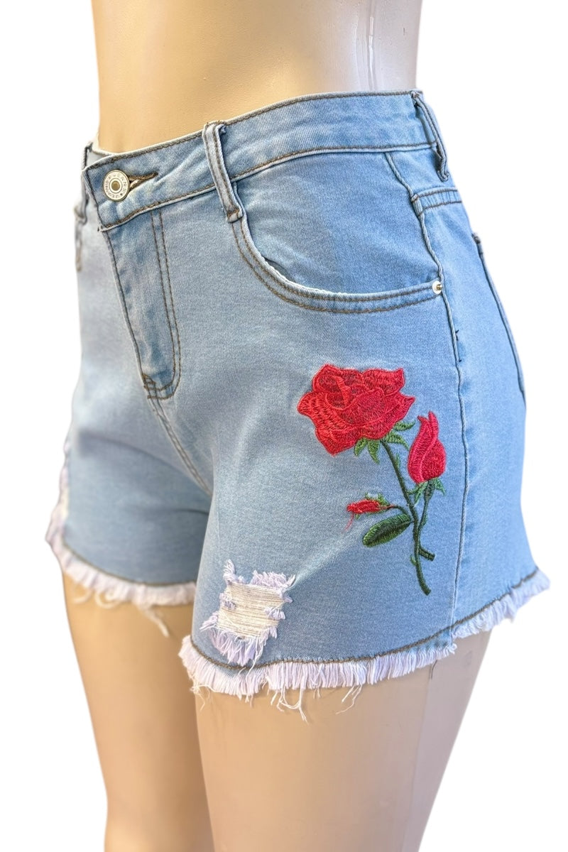 Denim shorts with red rose embroidery on a mannequin against a white background