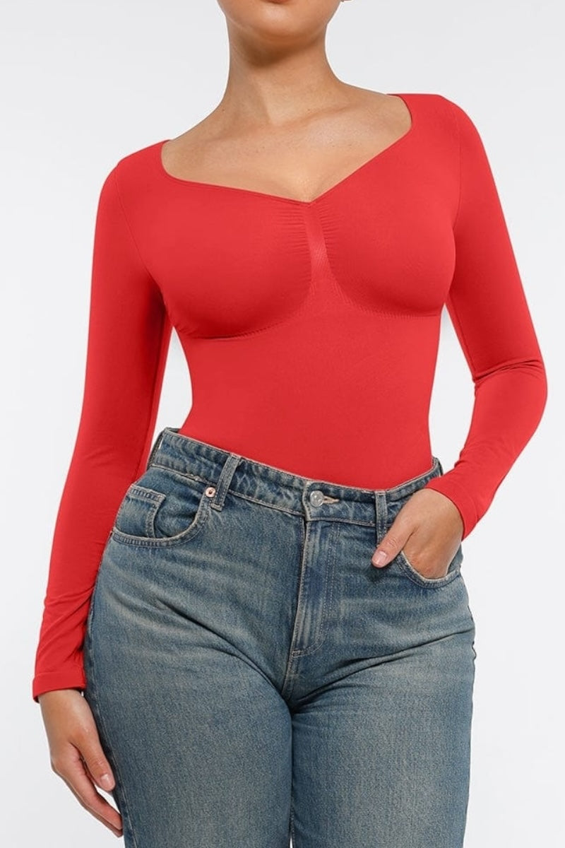 Person wearing a red long-sleeve top and blue jeans on a white background
