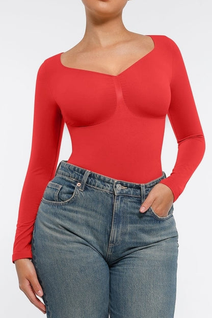 Person wearing a red long-sleeve top and blue jeans on a white background