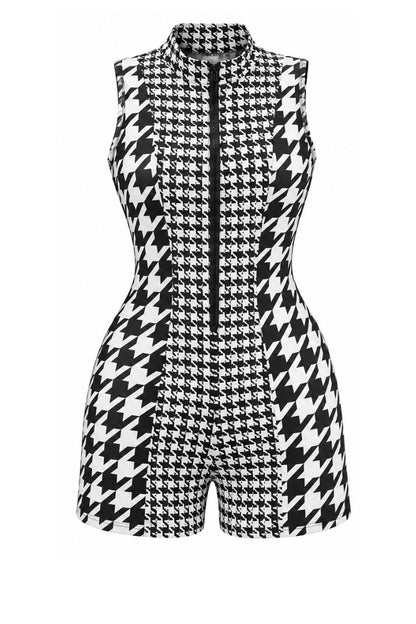 A sleeveless black and white houndstooth romper with a high mock neck and a central front zipper, shown on a plain white background.