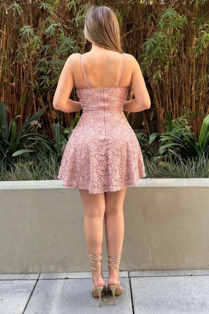 Woman wearing a pink lace dress standing outdoors with plants in the background